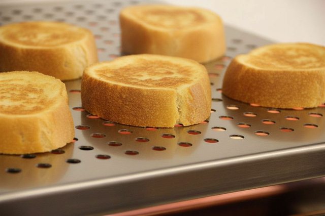 Brotscheiben werden auf dem gelochten Rost goldbraun geröstet