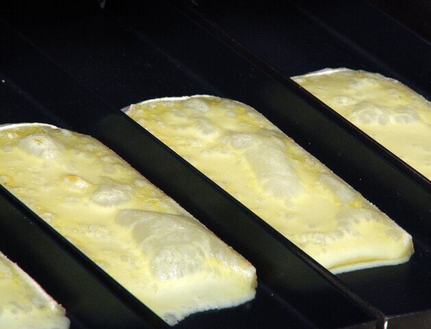 Blubbernder Raclettekäse in den Pfannen des Profi-Ofens